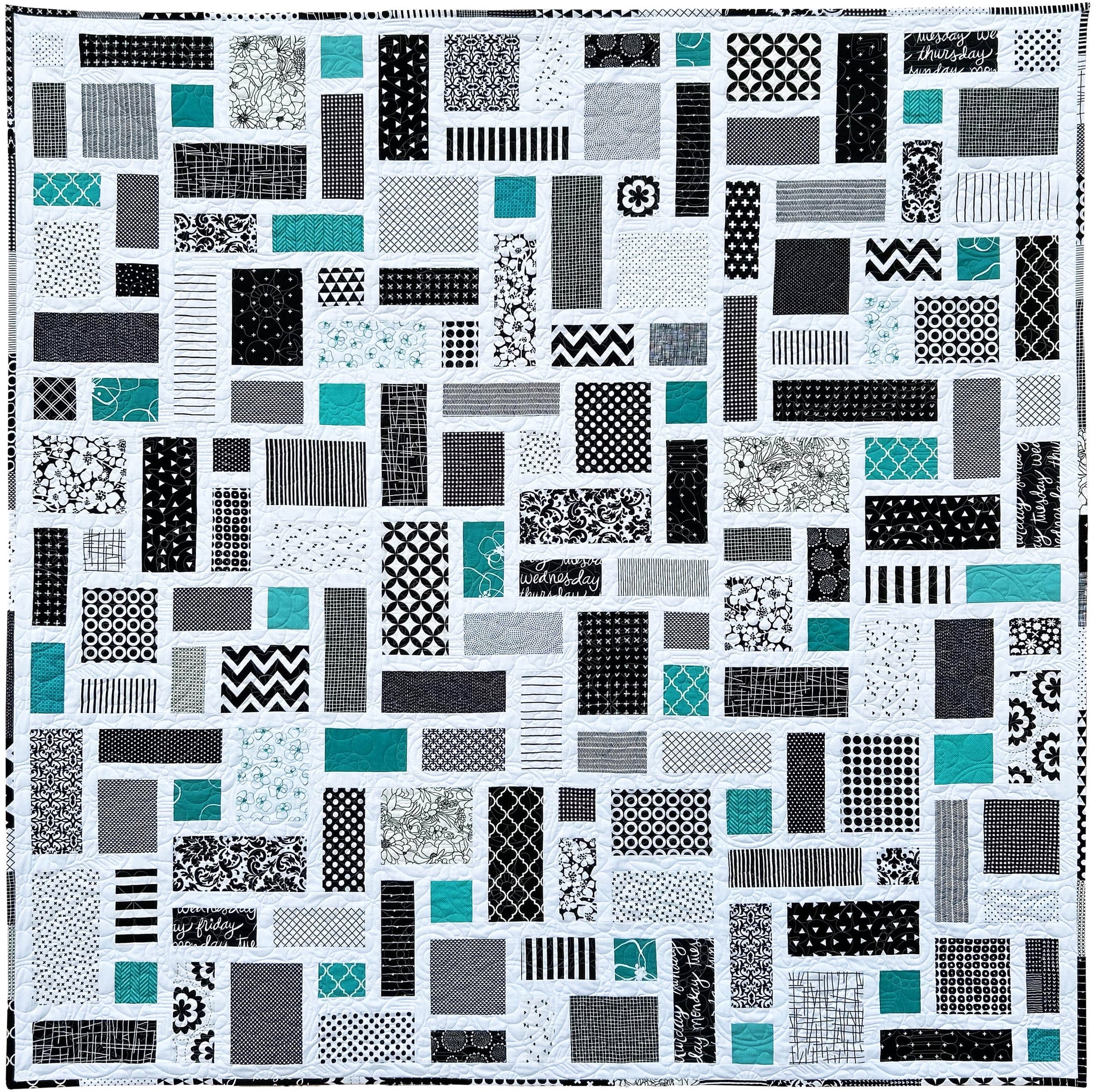 Black and White Quilt with a patchwork pattern of various geometric shapes and pops of jade green.