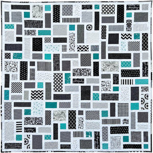 Black and White Quilt with a patchwork pattern of various geometric shapes and pops of jade green.