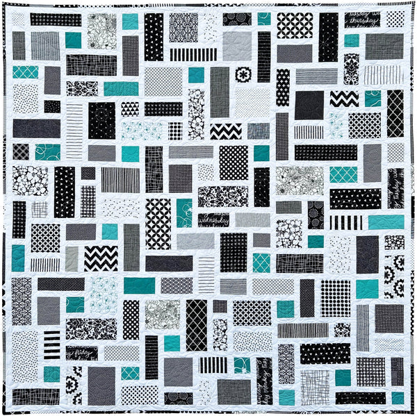 Black and White Quilt with a patchwork pattern of various geometric shapes and pops of jade green.