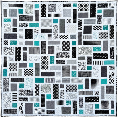 Black and White Quilt with a patchwork pattern of various geometric shapes and pops of jade green.